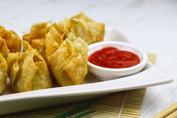 Siomay Goreng or Pangsit Goreng, Indonesian popular street food, made from fish and shrimp wrapped with dumpling wrapper, deep fried, served with chili sauce or peanut sauce. Selective focus. 
