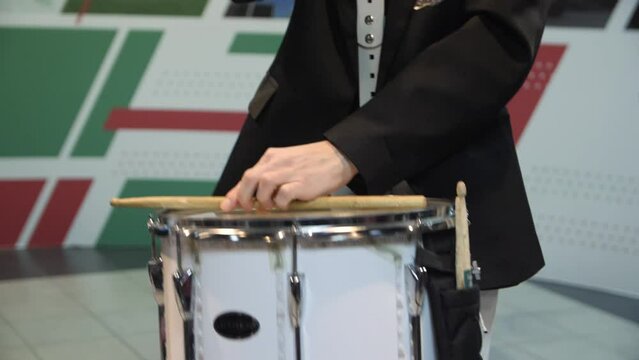 Young musician in black suit plays drum supporting hockey team on ice rink at sports stadium close view slow motion