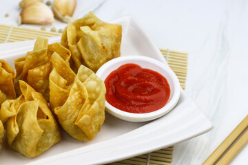 Siomay Goreng or Pangsit Goreng, Indonesian popular street food, made from fish and shrimp wrapped with dumpling wrapper, deep fried, served with chili sauce or peanut sauce. Selective focus. 