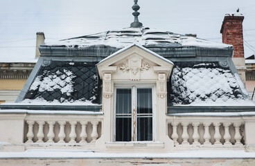Roof with attic and snow-covered tiled roof and white balustrade. Potocki Palace in Lviv, Ukraine.