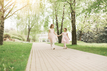 Fototapeta na wymiar two little sisters walking along the path of the city park.