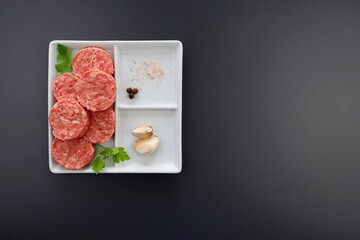 Fresh Mini beef burgers in a square plate on a gray background. Raw semi-finished meat products.