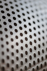 Metal fragment, chrome-plated surface with perforations in the form of round holes, metal colander. Close-up