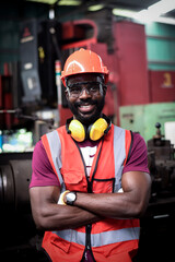 portrait of Happy african-american man worker have unkempt beard in safety uniform wearing helmet,glasses, vest and glove in industrial manufacturer factory.
