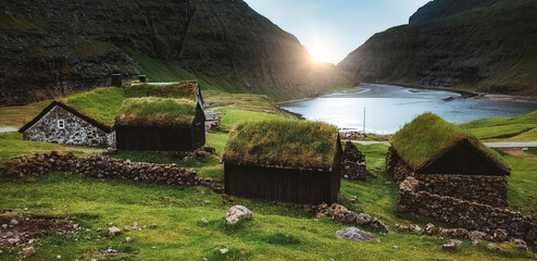 Spectacular view of the fairytale Saksun village in Faroe Islands at dawn. Traditional green roof houses and lagoon Pollurin in the background. - obrazy, fototapety, plakaty