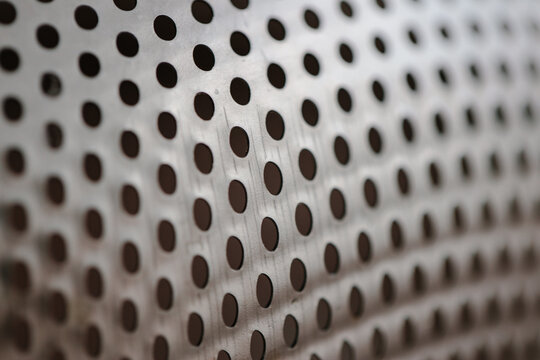 Metal fragment, chrome-plated surface with perforations in the form of round holes, metal colander. Close-up © AndreyZayats