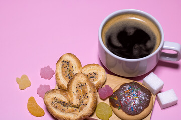 A cup of black coffee with marmalade on a pink background.