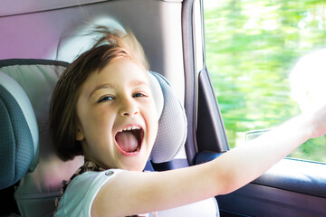 Little happy girl  in a car near the open window. Kid on a road trip. Shallow depth of field.