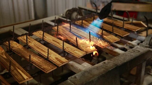Semi-automatic machine for brushing wooden parts with an open fire. The wood treated with fire becomes less combustible and is practically not subject to rotting and spoilage by insects.
