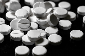 Close up of white painkiller tablet on a reflective black background