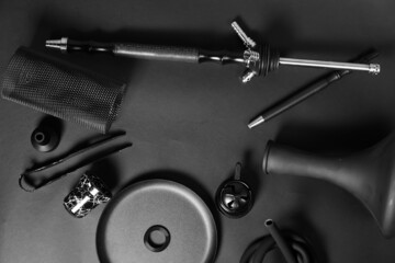 Black Egyptian Khalil Mamoon hookah details on the table: water pipe, charcoal bowl, glass flask, clay tobacco bowl, charcoal, tongs. Arabic shisha Concept. Dark background with calabash