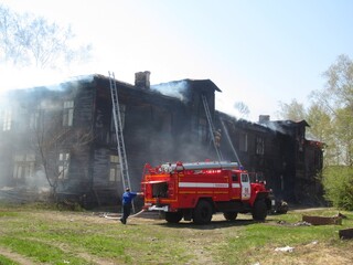 A fire truck on the background of a burning wooden house