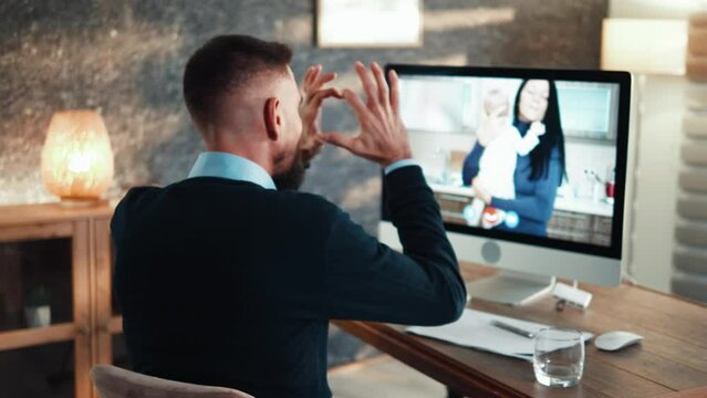 Rear view of business man working  while talking to her wife and son using computer 