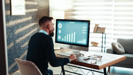 Satisfied business man using computer analyzing charts and graphs on a computer monitor. 