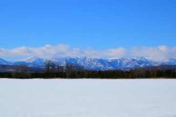 Fototapeta na wymiar 山と青空と平原、そして雪