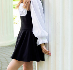 Young female student posing in a white blouse and black skirt in the park 
