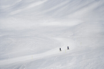 Snowy slopes with ski riders in sunny day. Ski resort Gudauri, Georgia. Caucasus Mountains. Aerial view. - 497730102