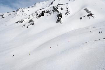 Snowy slopes with ski riders in sunny day. Ski resort Gudauri, Georgia. Caucasus Mountains. Aerial view. - 497730149
