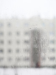 wet window glass overlooking a high-rise building