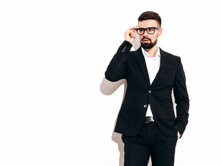 Fototapeta premium Portrait of handsome confident stylish hipster lambersexual model. Sexy modern man dressed in elegant black suit. Fashion male posing in studio near white wall. Isolated on white. In spectacles
