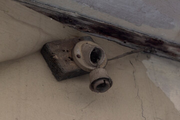 Close-up shot of an old, damaged lamp holder with no bulb on a cracked wall