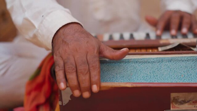 Closeup shot of Hands of an Indian street performer playing harmonium while singing at Jaisalmer in Rajasthan, India. Street performer playing harmonium in the side of the road. 
