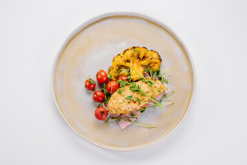 Dietary dish of chicken fillet with baked cauliflower, cherry tomatoes and microgreens