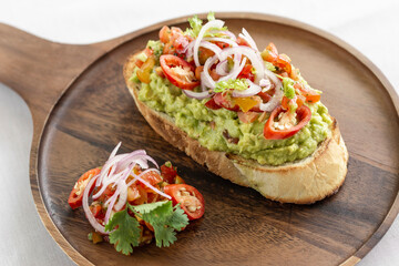 spicy chilli avocado guacamole on toast tapas on wood tray