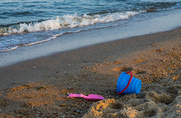 Children's toys on a sandy beach, blue sky and the sea in the background