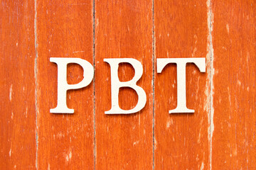 Alphabet letter in word PBT (Abbreviation of Profit before tax) on old red color wood plate background