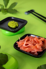 Wasabi and ginger condiments for Japanese cuisine on vivid green background.