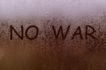 The inscription no war on the foggy window.