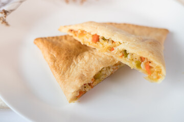 Vegetarian empanada cut into overlapping slices on a plate and white table