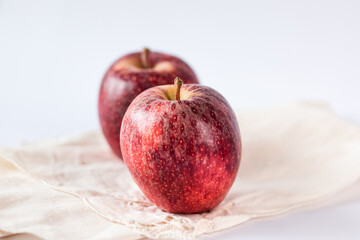 Two juicy and fresh red apples of biological origin arranged one behind the other on the white table. Horizontal photo.
