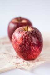 Two juicy and fresh red apples of biological origin arranged one behind the other on the white table. Vertical photo.
