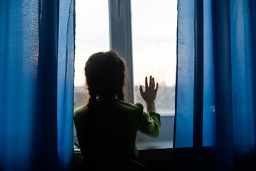 Young girl at window hands pressed against window, pensive or wanting out