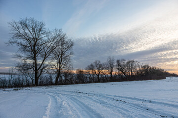 Obraz premium Natural sunset sunrise over field or meadow. The color of the sky over the winter snowy ground. Landscape under a picturesque sky at sunset. Dawn of the sun.