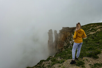 A girl on the background of two monks rocks in a cloud, Bermamyt plateau, Karachay-Cherkess Republic