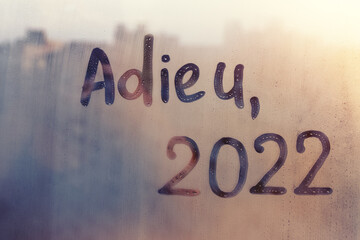lettering adieu in French is goodbye in english and numbers 2022 paint with finger of water on...