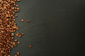 Coffee beans on black stone background. Roasted Coffee beans and black slate texture, top view,...