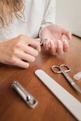 Close-up of hand of caucasian young woman doing manicure at home with nail supplies.