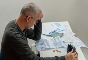 Mature man sitting at home, stressed and confused by calculate expense from invoice or bill, have no money to pay, mortgage or loan. Debt, bankruptcy or bankrupt concept