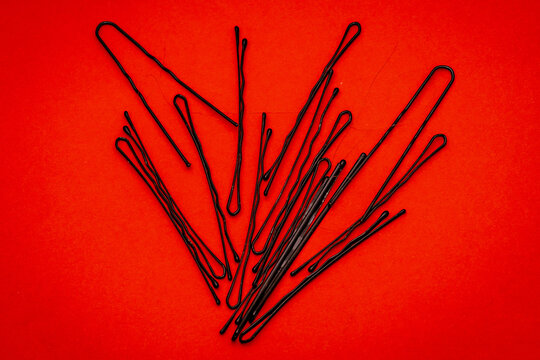 Metal bobby hair pins pile on red background