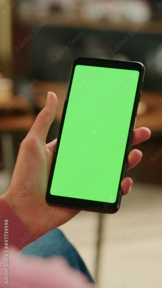 Poster Vertical Screen: Feminine Hand Scrolling Feed on Smartphone with Green Screen Mock Up Display. Female Resting at Home and Checking Social Media on Mobile Device. Close Up Over the Shoulder Footage.
