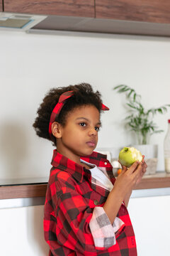 African-American Girl Eating An Apple In The Kitchen.Diverse People.Healthy Eating.Selective Focus,close Up.