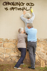 Old with an attitude. Shot of mischievous pensioners spray-painting graffiti on a wall.
