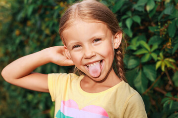 portrait of funny little girl with pigtails sticking her tongue out. Summer time and holidays