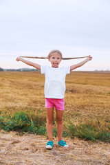 Cute little kid in white t-shirts having fun in field outdoor. Mock up.