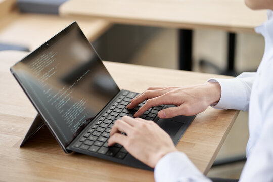 ノートパソコンでコードを書くアジア人プログラマー