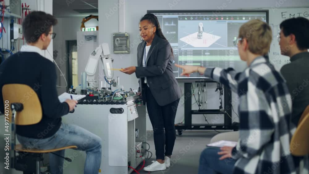 Poster Female Student Asking her Teacher while she Explaining Using Robot Arm at the Lesson. Diverse Group of Young Engineers Programming Robotic Hand. Computer Science Concept
